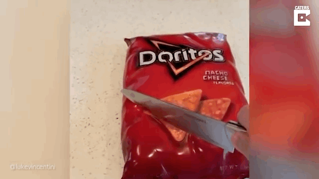 Gif of someone cutting into a bag of Doritos that is actually a cake