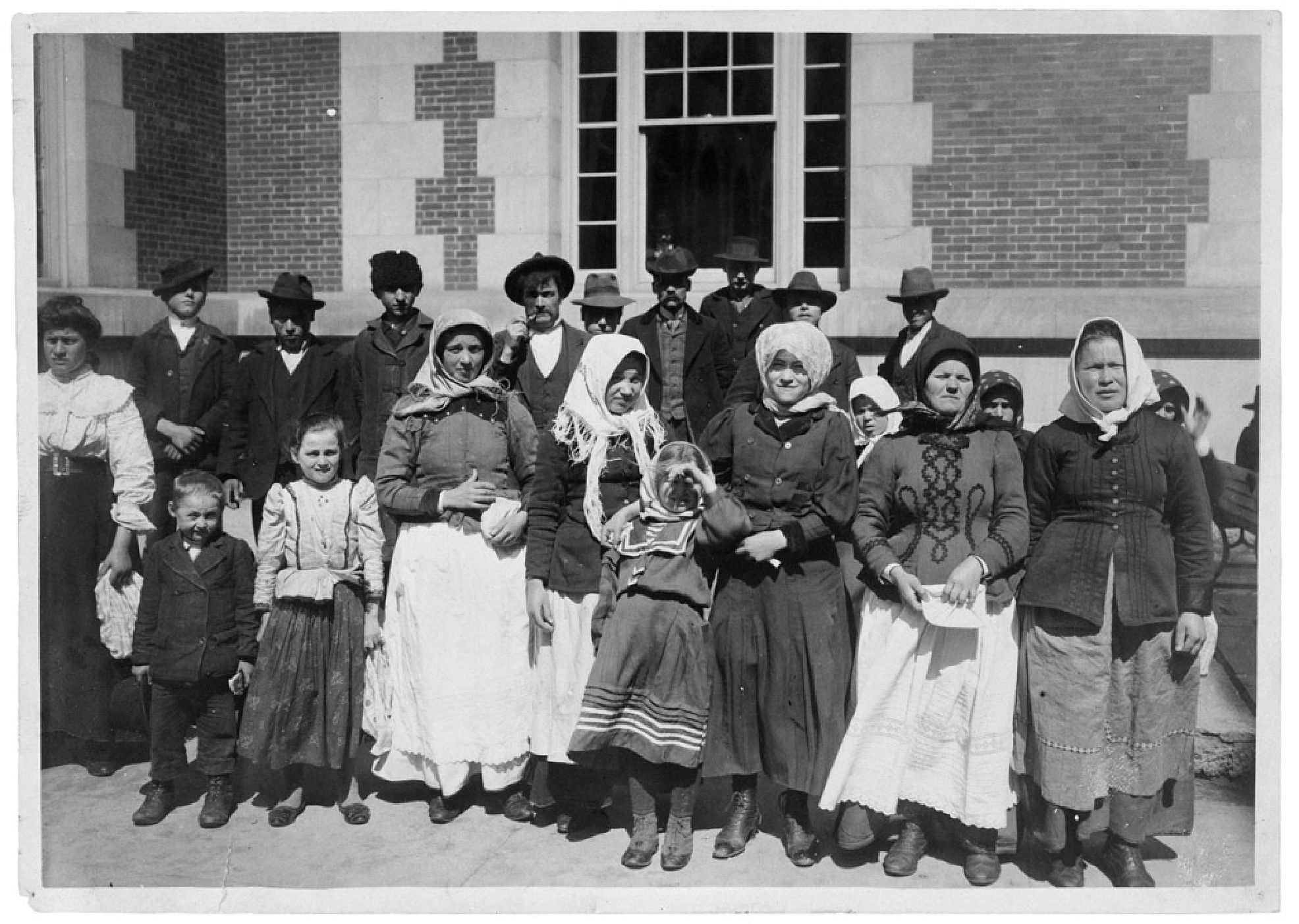 Immigrants outside a building on Ellis Island, circa 1900. 
